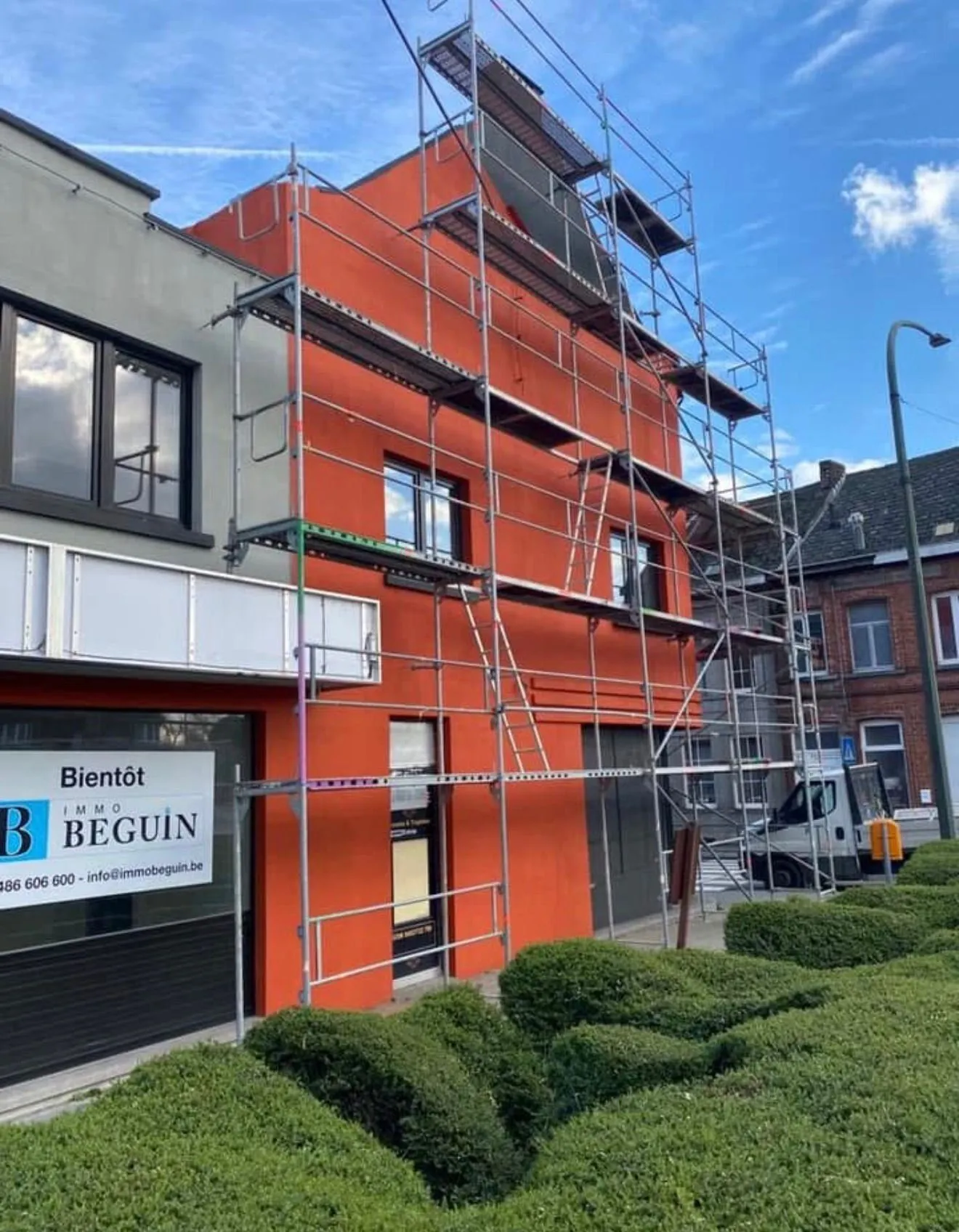 Appartementsgebouw met steiger tijdens gevelisolatie met roodoranje crepi