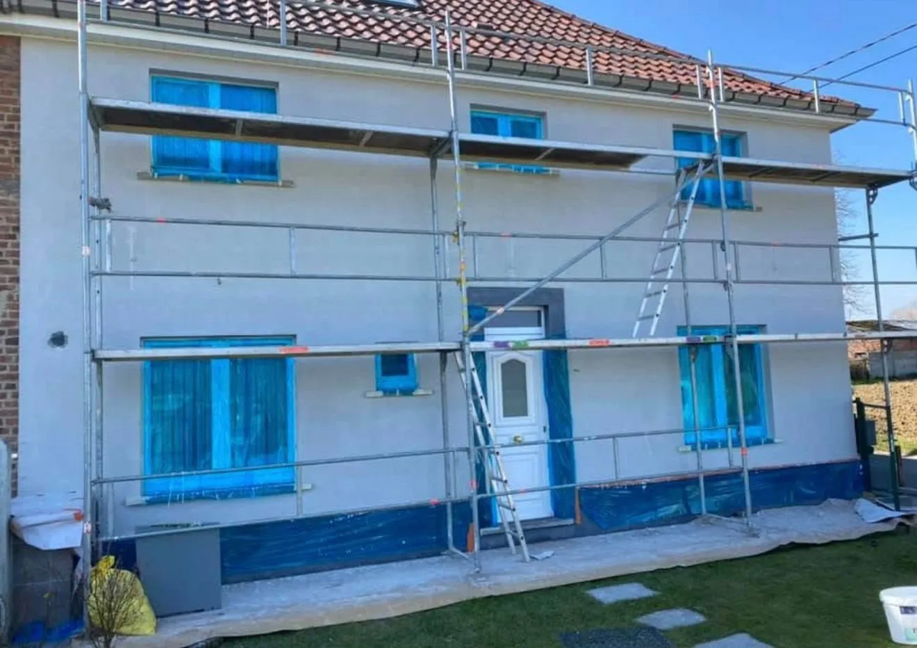 Woning met beschermde ramen tijdens het aanbrengen van crepi op gevelisolatie