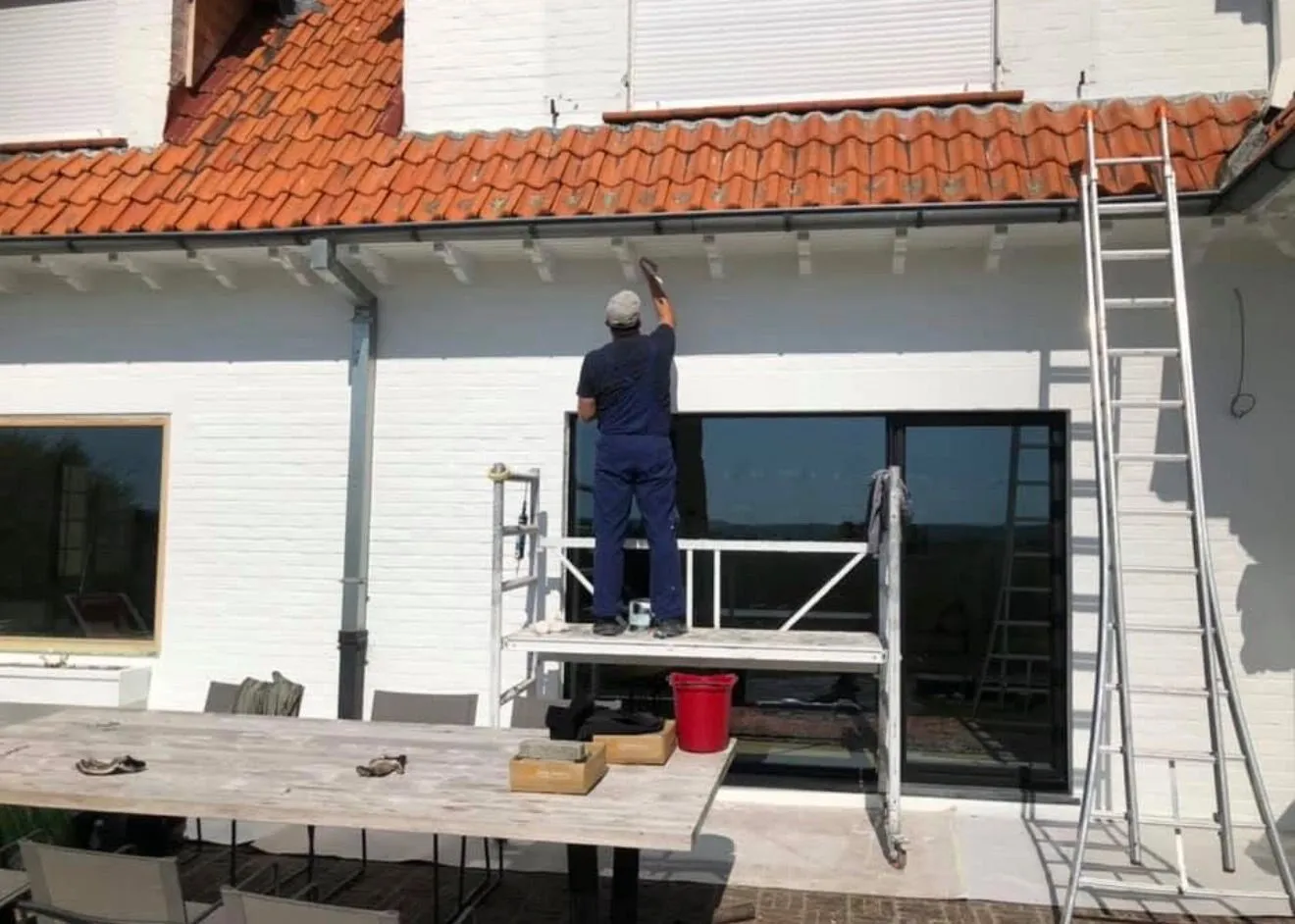 Vakman werkt de gevel af op een rolsteiger na de gevelrenovatie