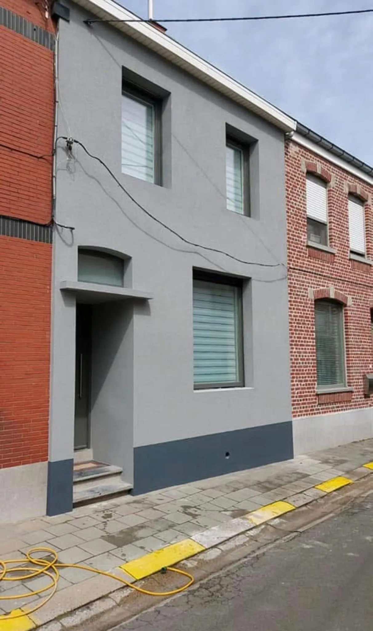 Rijwoning met nieuwe grijze crepi-gevel en donkere plint