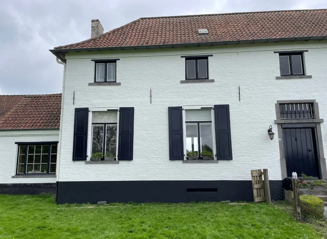 Gerenoveerde hoeve met witte crepi-gevel en zwarte luiken
