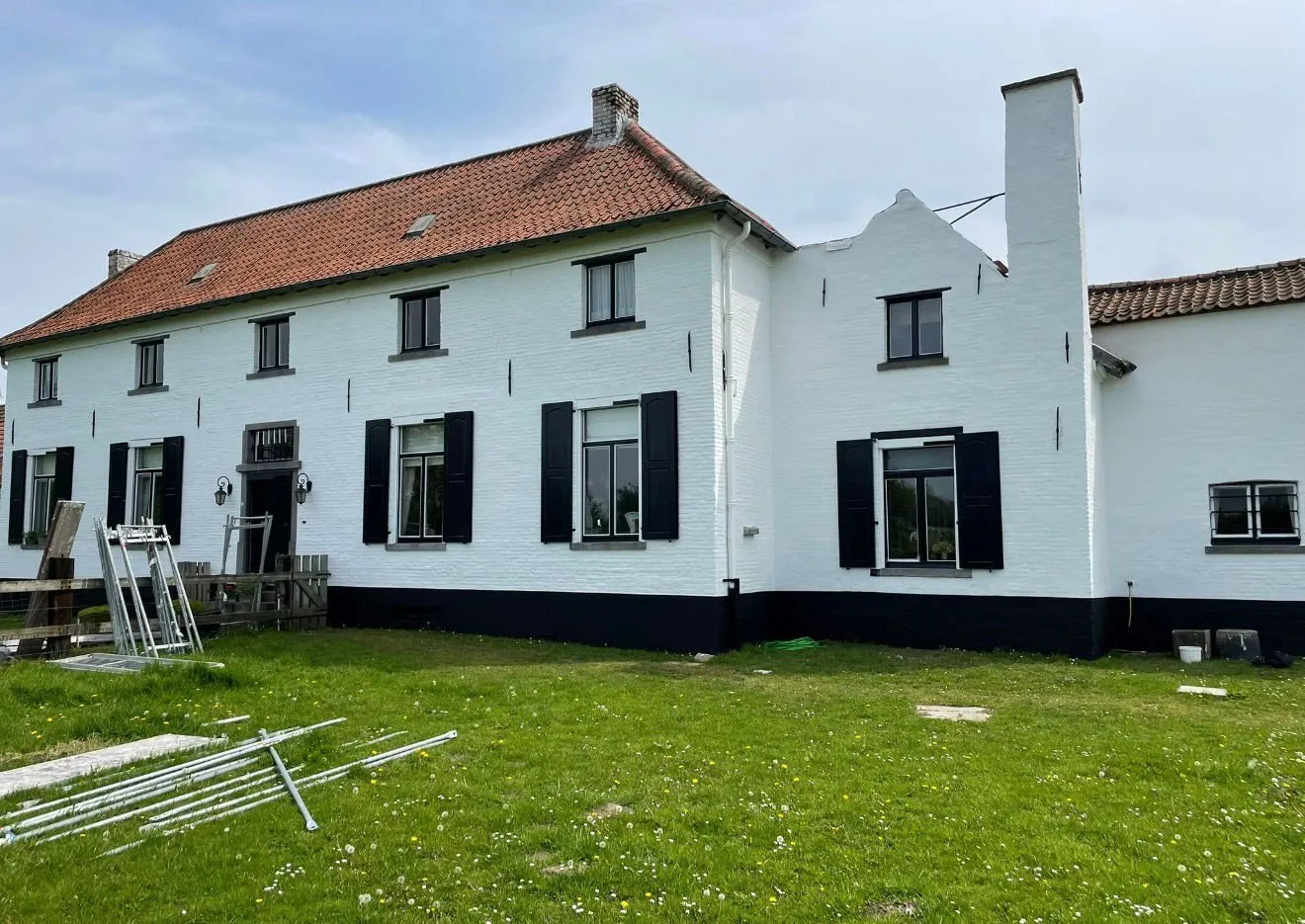 Witte villa met gerenoveerde gevel, zwarte luiken en pannendak