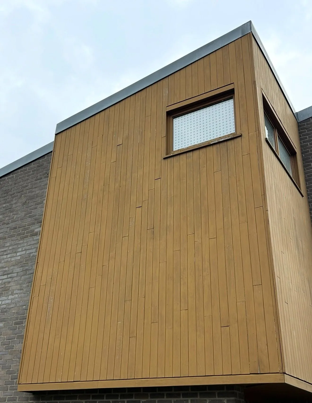 Moderne aanbouw met verticale houten gevelbekleding en strak raamkader