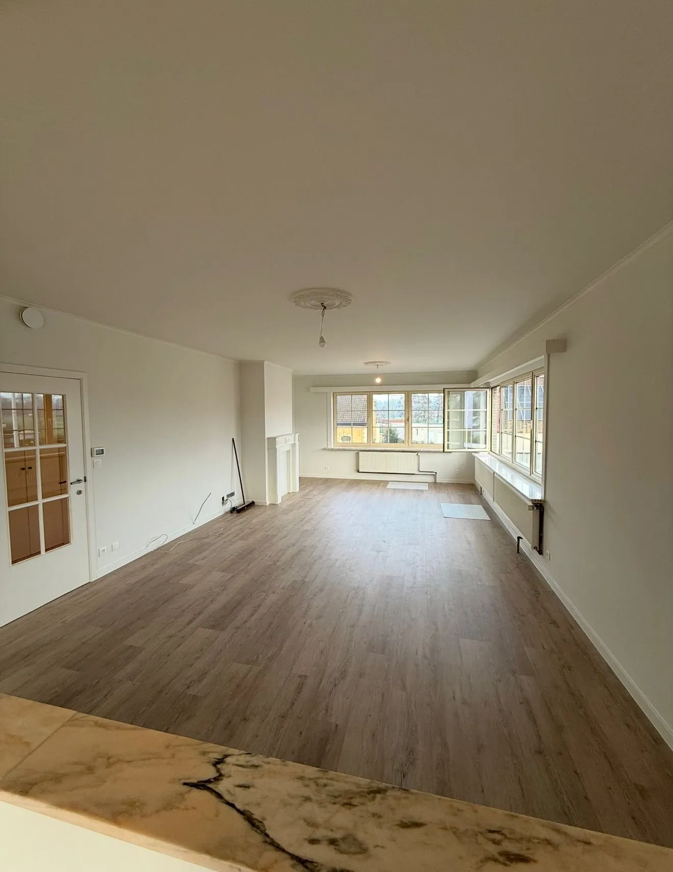 Afgewerkte leefruimte met nieuwe houten vloer na de renovatie
